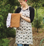 This chicken scratch apron has pictures of different colored chickens,with a beige color. 