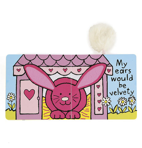 The book is shown open to two pages of a red rabbit with textured ears peeking out from a pink house in a field. The words "My ears would be velvet" are shown to the right in black lettering.