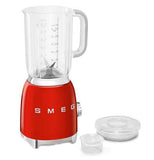 A blender with a red base is on its' base. The top is beside the blender, and taken apart to reveal that it's actually two pieces.