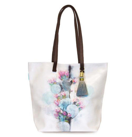 White bucket tote featuring a blue and pink cactus design with blue and grey tassel and brown handles.