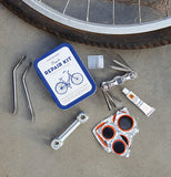 A bicycle tire lies on a sidewalk with the bicycle repair kit and its contents next to it.