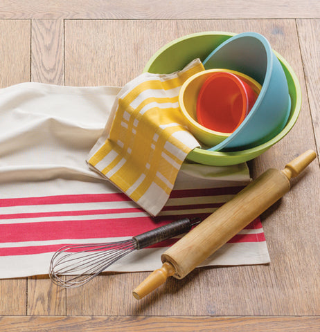 These 4 nesting bowls are sitting on a table with other mixing products.