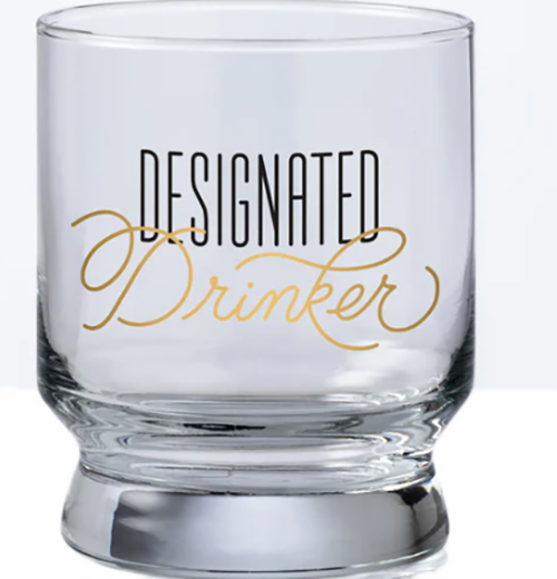 A bar glass with the words "Designated drinker" on it in black and gold text.