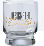 A bar glass with the words "Designated drinker" on it in black and gold text.