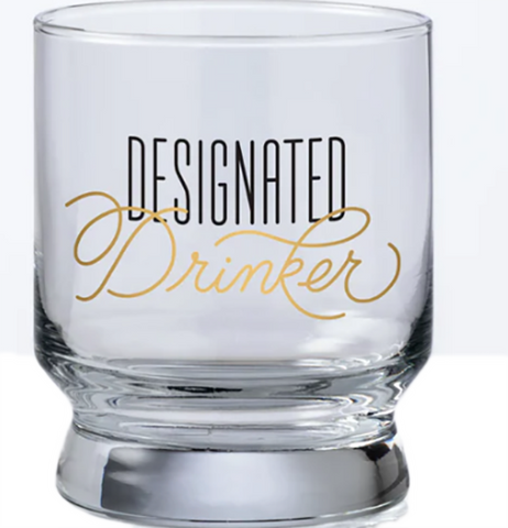 A bar glass with the words "Designated drinker" on it in black and gold text.