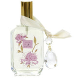 Perfume has a gold top with pink flowers and two crystals.