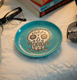 The Cuppa Color "Blue Skull" Coaster sits with the glasses, the textbooks, and the wristwatch on the mattress. 