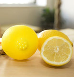 Half a lemon sitting next to a lemon squeezer.