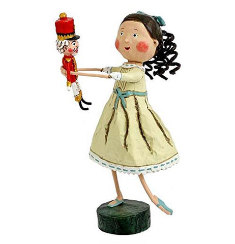 This figurine is of a girl named Clara wearing a white dress with a blue sash, holding a nutcracker doll.