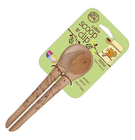 This beechwood spoon has a set of two handles very close together. On the two handles are pictures of flowers on tree branches. At the top of the spoon, holding a flower, is a hedgehog. The spoon is attached to its green packaging with the words, "Coffee Scoop & Clip" in brown lettering.