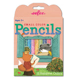 This box of colored pencils depicts a fox and raccoon drawing each other from opposite sides of a window. The fox is outside the house, sitting on a tree stump on grass, while the raccoon is shown inside the house. Behind the raccoon is an opening to show the different colored pencils. Above the open window shutters are the words, "Small Color Pencils" in red and green lettering.