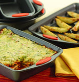 Lasagna and potato wedges are shown being served from two pans.