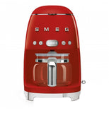 A red coffee machine with a coffee carafe set up inside it. The base has small "feet" that elevate it slightly. The brand name "Smeg" and buttons are across the body.