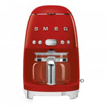 A red coffee machine with a coffee carafe set up inside it. The base has small "feet" that elevate it slightly. The brand name "Smeg" and buttons are across the body.
