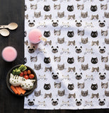 Cat's meow dish towel laying out like a picnic blanket with veggies, drinks and silverware on it.
