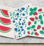 The "Blueberries" Swidish dishcloth lays between the "Watermelons" and "Strawberries" dishclothes. 