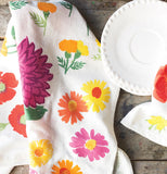 this flowered floral tea towels have different types of flowers on them and is sitting on a wooden table alongside a white salad plate