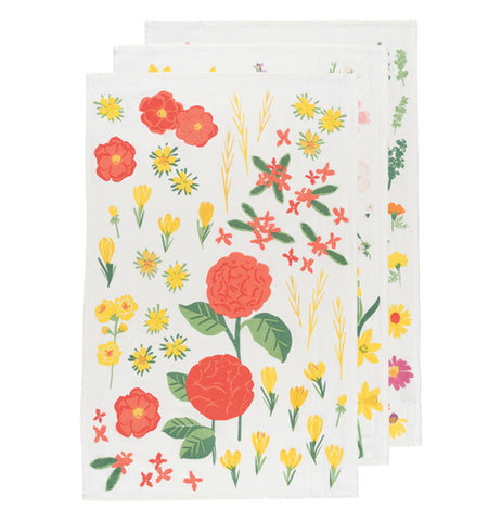 Three white tea towels with floral pattern laid out for display