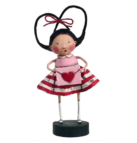 Girl figurine with pig tails tied with a red ribbon in a heart shape wearing a pink blouse and red and white striped skirt holding a pink envelope with red heart on it. 