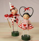 Boy and girl Valentines Day figurines. Boy in a clown costume holding a wand with heart on the end. Girl in a pink blouse and red and white striped skirt combo holding a pink envelope with a heart.