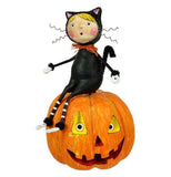 This figurine is of a boy dressed in a black cat costume sitting on top of a smiling jack-o-lantern.