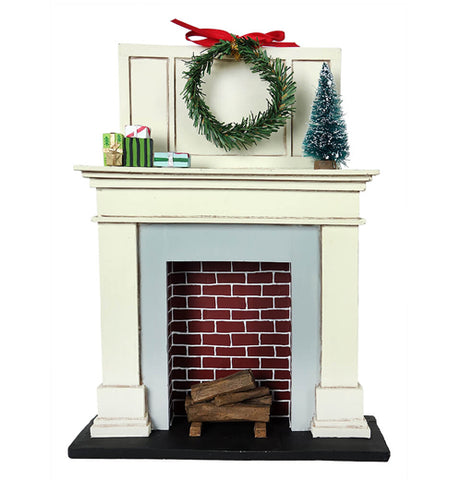 This miniature sculpture is of a fireplace with logs in it and a Christmas wreath hanging above the mantle. On the mantle sits a miniature Christmas tree and some wrapped presents.