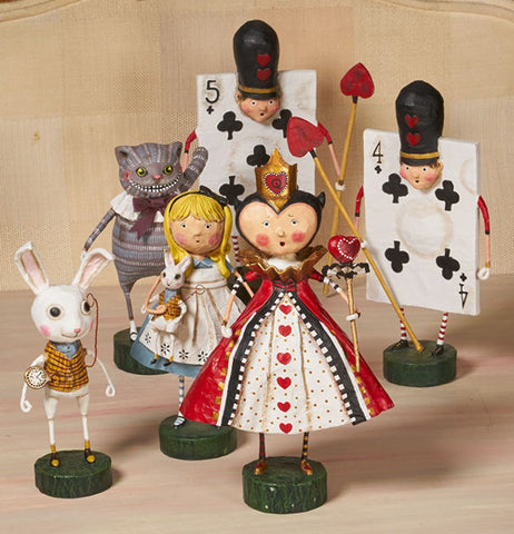 The Four of Clubs figurine sits with other figurines from Alice In Wonderland on a wooden table.