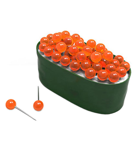 A container shaped like sushi with orange tacks that are made to resemble fish eggs sticking from the top with couple laying next to it.