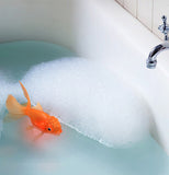 The orange koi fish toy is shown floating among bubbles in a bathtub.