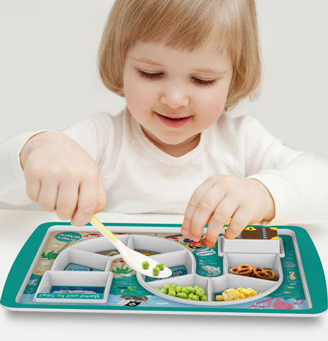 a little girl eating a snack from one of the many slots in the plate.