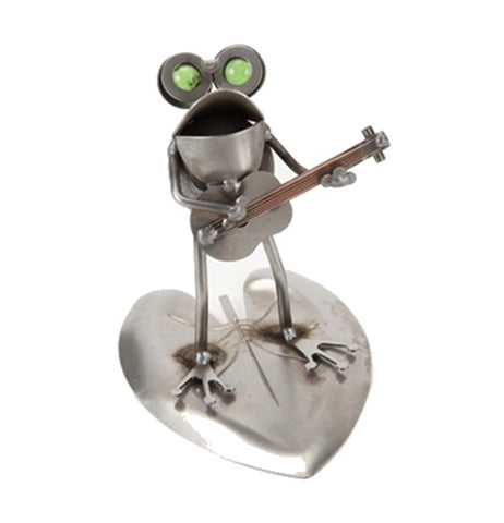 A scrap metal frog holds a guitar and appears to be singing. It's on a lily pad. The eyes are green.