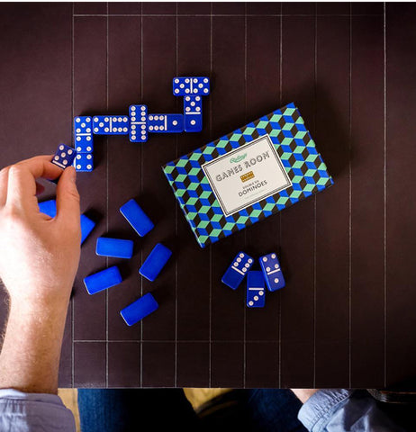 Someone playing Dominoes on a brown table.