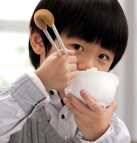 Boy eating rice with these fortune cookie chopsticks.