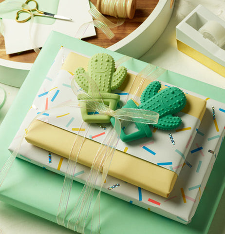 One light green and the other dark green cactus, on a pile of presents.