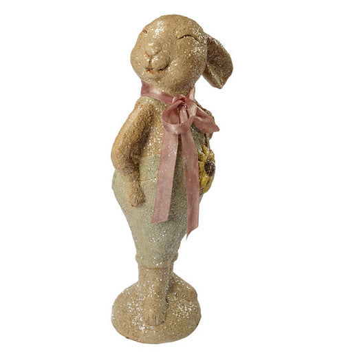 A statue of a smiling beige bunny with a pink ribbon.