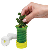 This herb keeper is dark green on the top half; the bottom half is lime green. It has a white lid laying next to it. There's a hand putting cilantro in it.