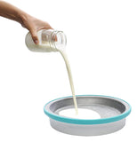 Pouring milk for ice cream from glass cup into the pan with the turquoise edges