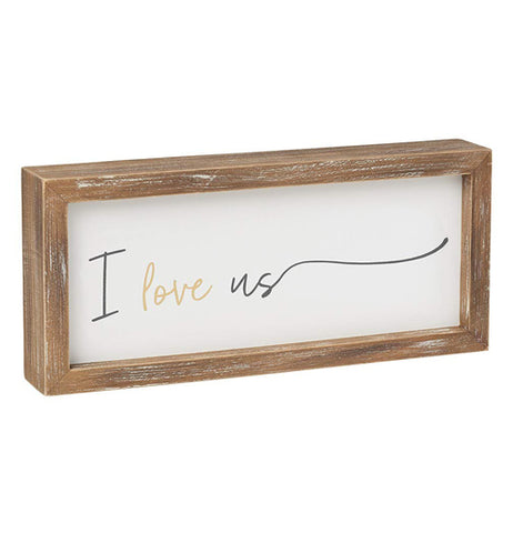 This wooden box sign has a white background with the words, "I Love Us" in yellow and black lettering.