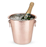 Hammered copper ice bucket with ice and bottle of champagne with handles.