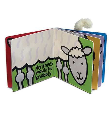 The book is shown standing up and opened to green pages with a side view of a white lamb with a grey face and legs. The words, "My Knees would be knobbly" are written in black between the lambs front and rear knees.
