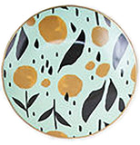A small blue, green or teal dish has yellow and black plants painted on it.