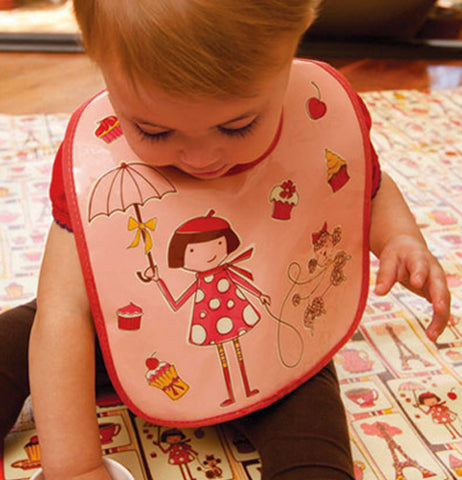 The baby laying on the Jumbo Floor Splat Mat in Cupcake while wearing an apron with the same pattern.