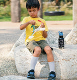 A Boy playing with his airplane with his black insulated water bottle with white drawing on it with a blue sports cap.
