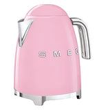 A light pink tea kettle has a silver handle with a silver spout, the base is also silver and the logo "Smeg" on its side
