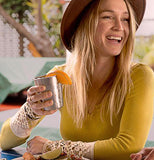 This image shows a young woman in a yellow sweatshirt wearing a hat and holding a lemon in the steel cup.