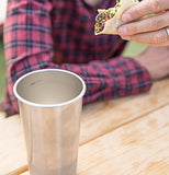 This image shows the cup standing next to a man with a black and red striped sweater eating a taco.