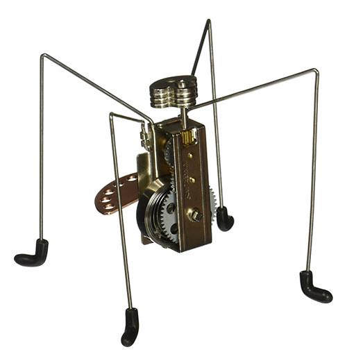 This little metal wind-up toy is shaped like a four-legged spider with a gray metal wind-up handle in the back and black socks on its feet.