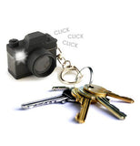 The black camera-shaped keychain is shown attached to a set of different keys.