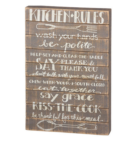 Slat Sign with "Kitchen Rules" written out on it with white letters and a wooden background.