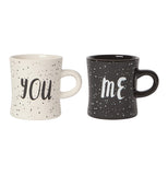 Set of 2 mugs one white that reads "You" in black with black specks and one black that reads "Me" in white with white specks over a white background.